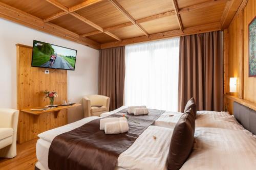 a hotel room with a large bed and a flat screen tv at Landhaus St. Georg in Gröbming