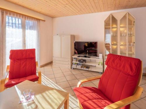 a living room with two red chairs and a tv at Apartment Hübeli - Moosmatten by Interhome in Zweisimmen