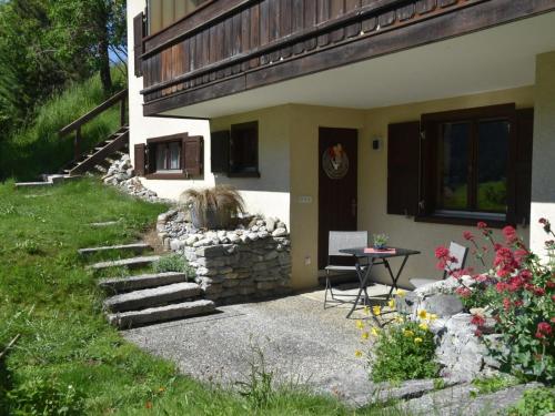 a house with a stone wall and a table in the yard at Apartment Am Sonnenhang by Interhome in Churwalden