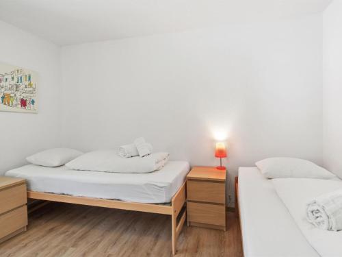 two beds in a room with white walls and wooden floors at Apartment Seeli by Interhome in Churwalden