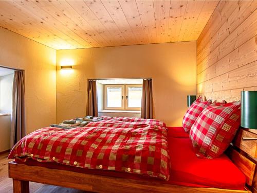 a bedroom with a red bed and a window at Apartment Ferienhaus Tgioc by Interhome in Obervaz