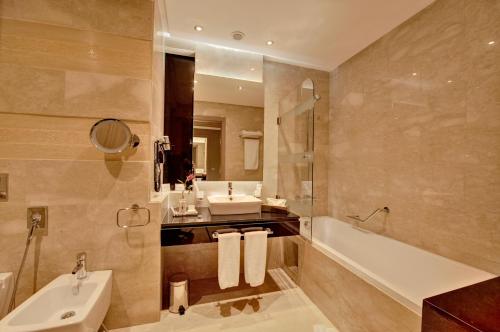 a bathroom with a sink and a tub and a toilet at Royal Tulip City Center in Tangier