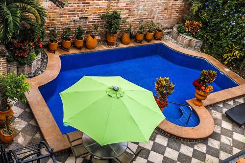 a green umbrella sitting next to a swimming pool at Casa del Sol Inn in Ajijic