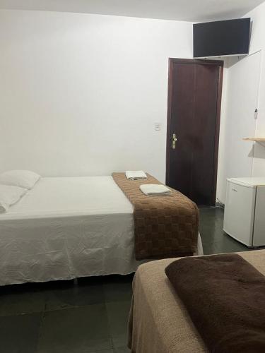 a hotel room with two beds and a cabinet at Pousada e Restaurante Dona Lu in Itaperuna