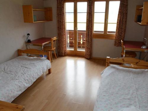 a room with two beds and a table and a window at Apartment Henry - 1- Stock by Interhome in Schönried