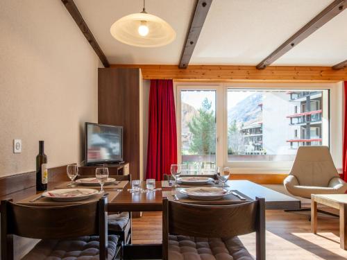 une salle à manger avec une table, des chaises et une télévision dans l'établissement Apartment Haus Azur by Interhome, à Saas-Almagell
