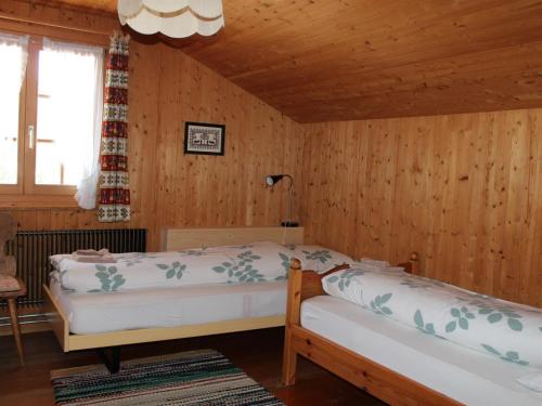 a bedroom with two beds in a room with wooden walls at Apartment Beatrice by Interhome in Schönried