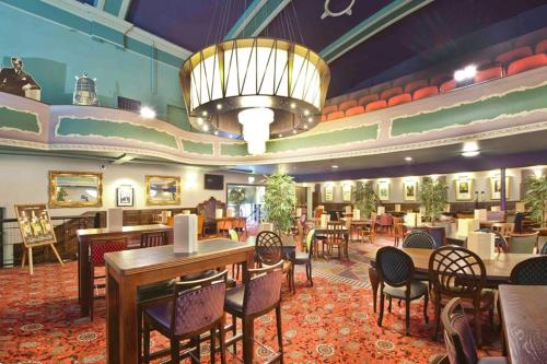 um restaurante com mesas e cadeiras e um lustre em The Hippodrome Wetherspoon em March