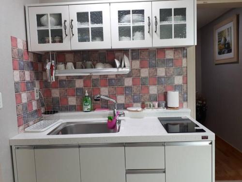 a kitchen with white cabinets and a sink at Gozneok spacious private house - 75py in Goseong