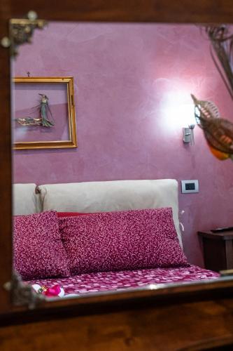 a bedroom with pink walls and a bed with purple sheets at a casa di Ma Gi in Ciampino