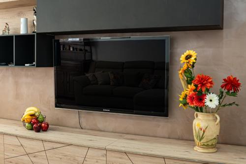 a vase of flowers on a table with a television at a casa di Ma Gi in Ciampino