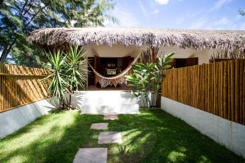 a small house with a thatch roof and a fence at A Piscina Itaca in Barrinha