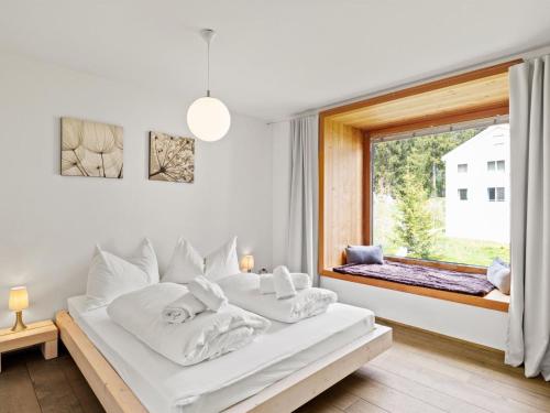 a bedroom with a bed with white sheets and a window at Apartment Kulm 2 by Interhome in Valbella