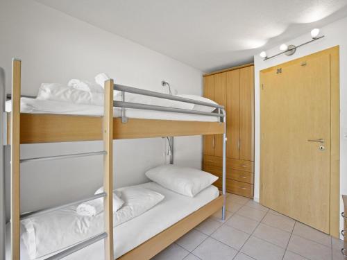 a bunk bed room with two bunk beds and a door at Apartment Ruggli by Interhome in Churwalden