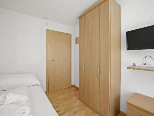 a bedroom with a bed and a wooden cabinet at Apartment Ruggli by Interhome in Churwalden