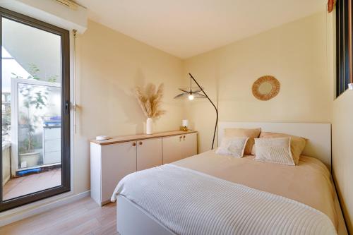 a bedroom with a bed and a large window at Le Molière des Bords de Seine - 15 min de Paris in Asnières-sur-Seine