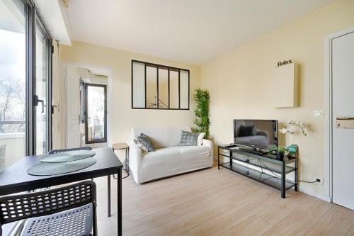 un salon avec un canapé blanc et une télévision dans l'établissement Le Molière des Bords de Seine - 15 min de Paris, à Asnières-sur-Seine