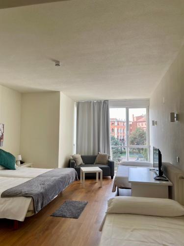 a bedroom with two beds and a couch and a window at Hotel La Mota by Punta25 Hotels Group in Medina del Campo