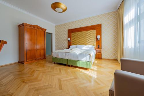 a bedroom with a bed and a wooden floor at Hotel Josefshof am Rathaus in Vienna