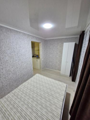 une chambre vide avec un lit et une cuisine dans l'établissement 2х-ком апартаменты в центре города Kvant, à Petropavlovsk-Kamtchatski