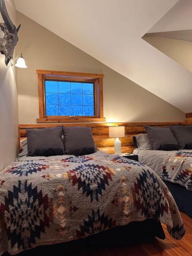 a bedroom with two beds and a window at Ryders Lodge, Log Home in Edgewater, BC in Radium Hot Springs