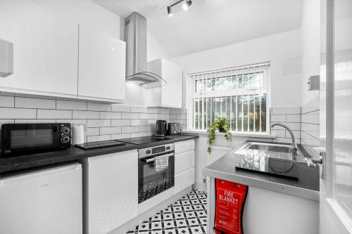 a white kitchen with a sink and a microwave at Two Bedroom Apartment - On Street Parking Available - Netflix - Wifi - Top Rated - 311M in Birmingham