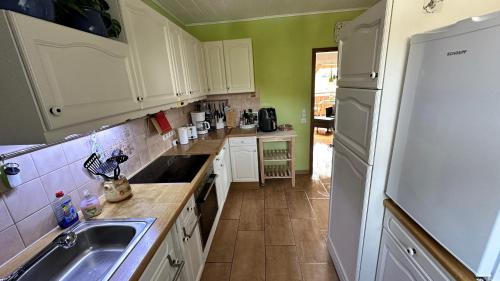 a kitchen with white cabinets and a sink and a refrigerator at Gästezimmer zum Waldsachsener Grund in Meerane