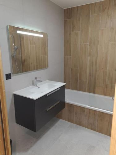 une salle de bain avec un lavabo, un miroir et une baignoire dans l'établissement Appartement 6 à 8 voyageurs, à Huez