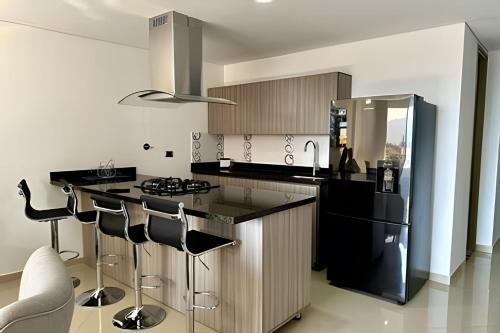 エンビガドにあるModerno Apt. Balcón con vista, rápido WiFi y ACのキッチン(黒い冷蔵庫、カウンター、スツール付)