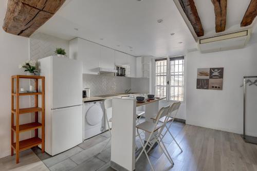 - une cuisine avec des appareils blancs, une table et des chaises dans l'établissement Bluestay 112 - Élégant Appartement à Paris, à Paris