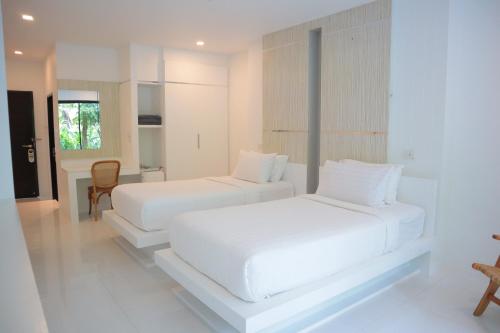 two white beds in a white room with a table at Ton Sai Tropical Phi Phi Island in Phi Phi Don