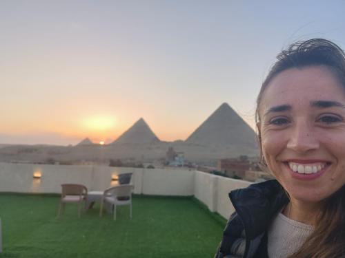 Una mujer parada en un tejado con pirámides al fondo. en Best four pyramids view, en El Cairo