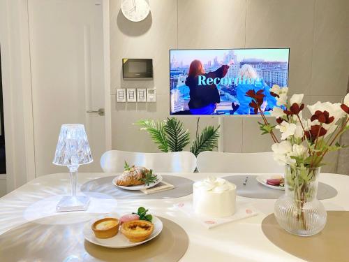 a white table with plates of food and a tv at The Hue stay, SEOUL in Seoul