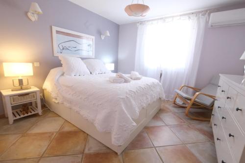 a bedroom with a bed with white sheets and a window at Vacation rental in the Alpilles, Provence, close to the village center - Beautiful view -Air conditionning Heated pool and spa - sleeps 8 in Aureille
