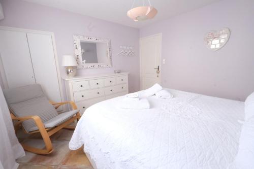 a white bedroom with a bed and a chair at Vacation rental in the Alpilles, Provence, close to the village center - Beautiful view -Air conditionning Heated pool and spa - sleeps 8 in Aureille
