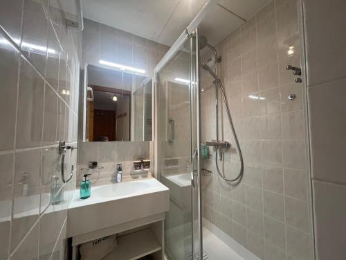 La salle de bains est pourvue d'un lavabo et d'une douche avec une porte en verre. dans l'établissement Cocooning apartment- 2 personnes - FR-1-198-221, à Châtel