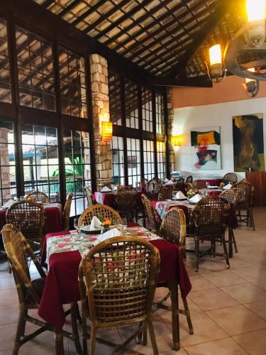 a restaurant with tables and chairs in a room with windows at Portal Lençóis in Lençóis