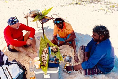 a group of men sitting around a table on the beach at Suncoral Maldives in Kondey
