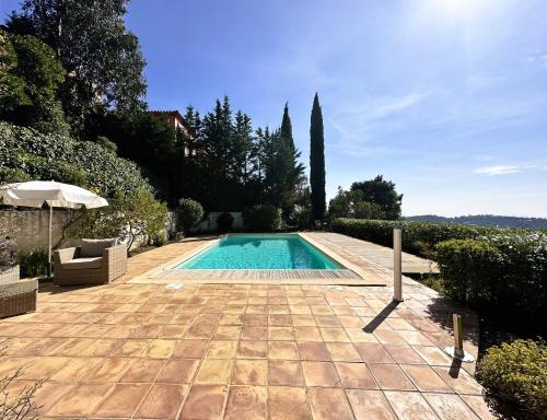 - une piscine dans un jardin avec un parasol dans l'établissement Villa Lougabie pour 8 personnes, vue mer et piscine sur le Domaine de Valcros à La Londe-Les Maures, à La Londe-les-Maures