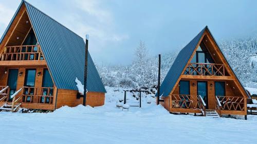 two large wooden homes in the snow with snow covered trees at Villa Wood in Mestia N 2 in Mestia