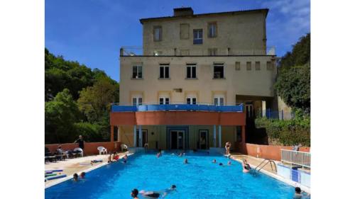 - une piscine en face d'un bâtiment avec des personnes dans l'établissement Rennes-les-Bains Studio at foot of thermal baths, à Rennes-les-Bains