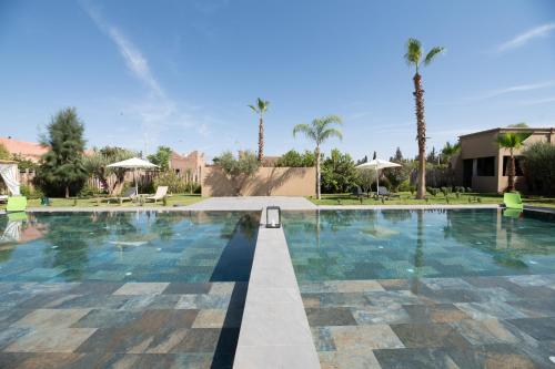 una piscina en un complejo con palmeras en Stylish hôtel, en Marrakech