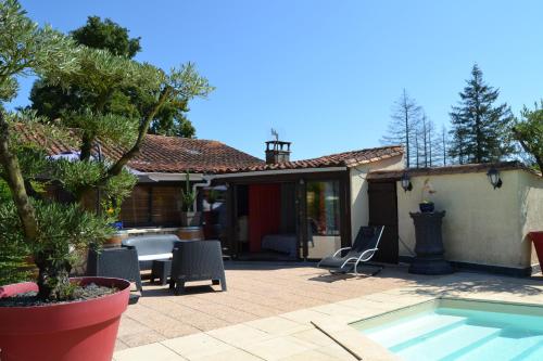 a patio with a table and chairs and a pool at Le gite de la Lombriere in Saint-Denis-de-Pile