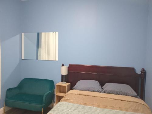 a bedroom with a bed and a green chair at Windspire Inn in Port Elgin