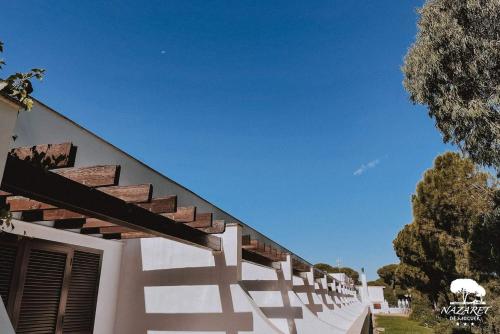 a white building with wooden steps and a blue sky at Complejo Turístico Rural Nazaret De Moguer in Moguer