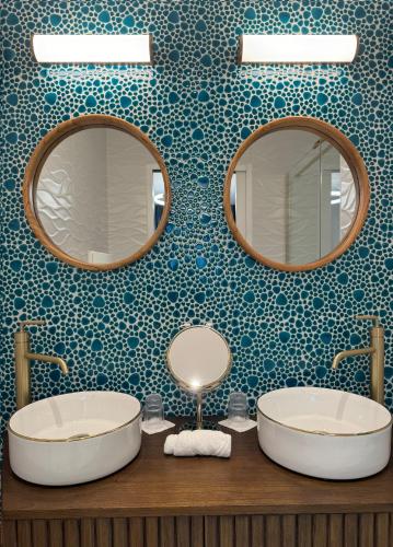 une salle de bain avec deux lavabos et deux miroirs dans l'établissement Domaine Les Clayères, à Talmont-Saint-Hilaire