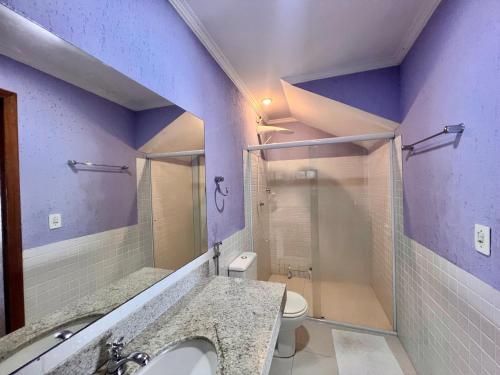 a purple bathroom with a sink and a toilet at Eco Sapê House in Angra dos Reis