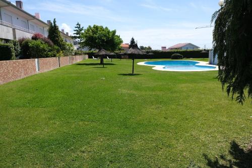 a large yard with a swimming pool and grass at high standard rental in a quality residence with pool, tennis and view of the ocean in antas esposende 12 people in Esposende