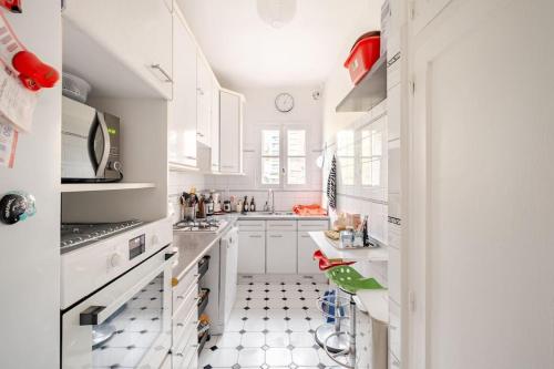 - une cuisine avec des placards blancs et du carrelage noir et blanc dans l'établissement Duplex spacieux, 10 min de Paris, à Puteaux