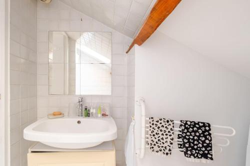 une salle de bain blanche avec un lavabo et un miroir dans l'établissement Duplex spacieux, 10 min de Paris, à Puteaux